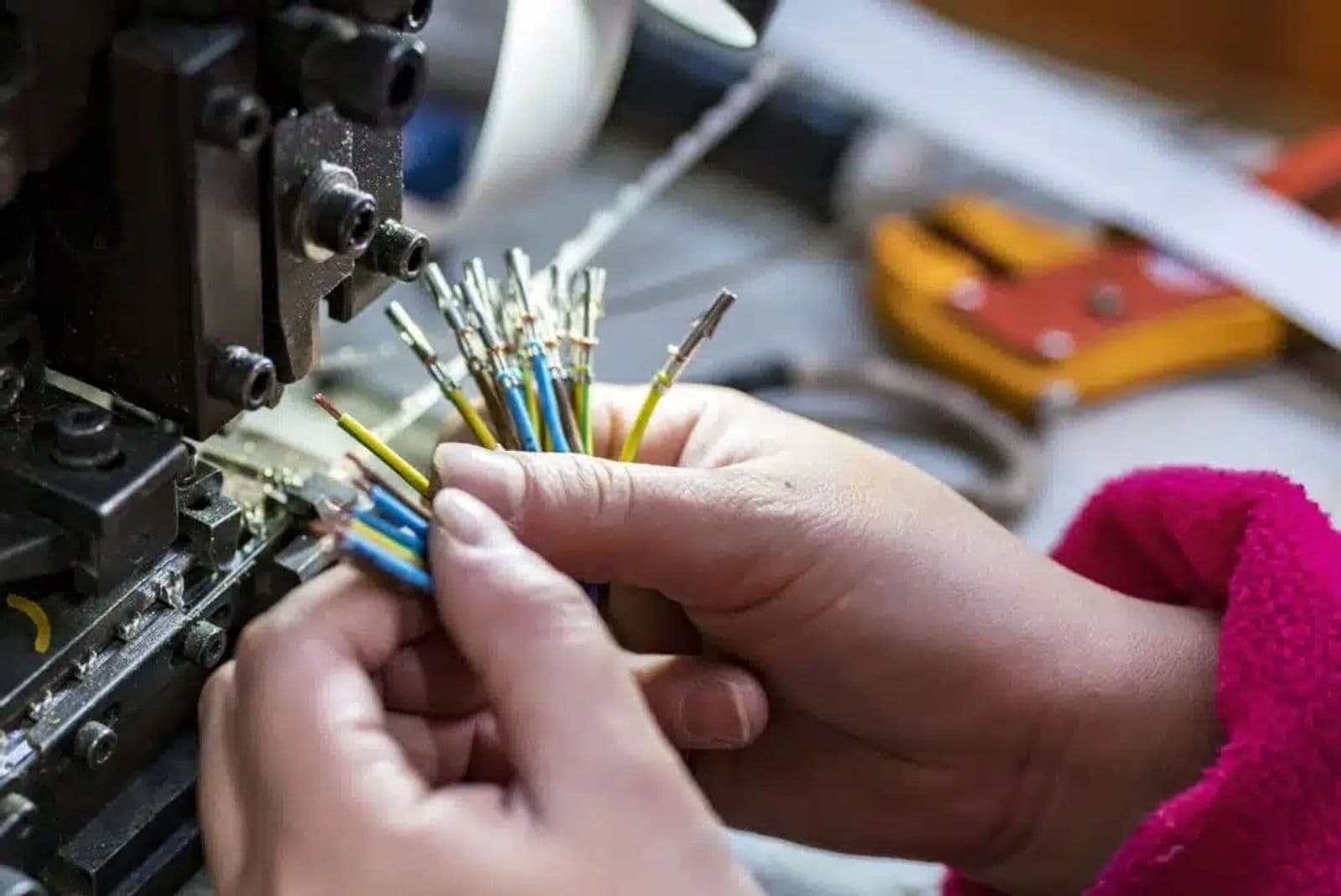 A technician crimping terminals onto electrical wires for a custom wire harness assembly.